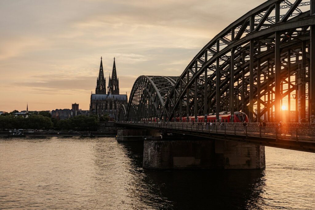 Train crossing a bridge with cathedral in background at sunset